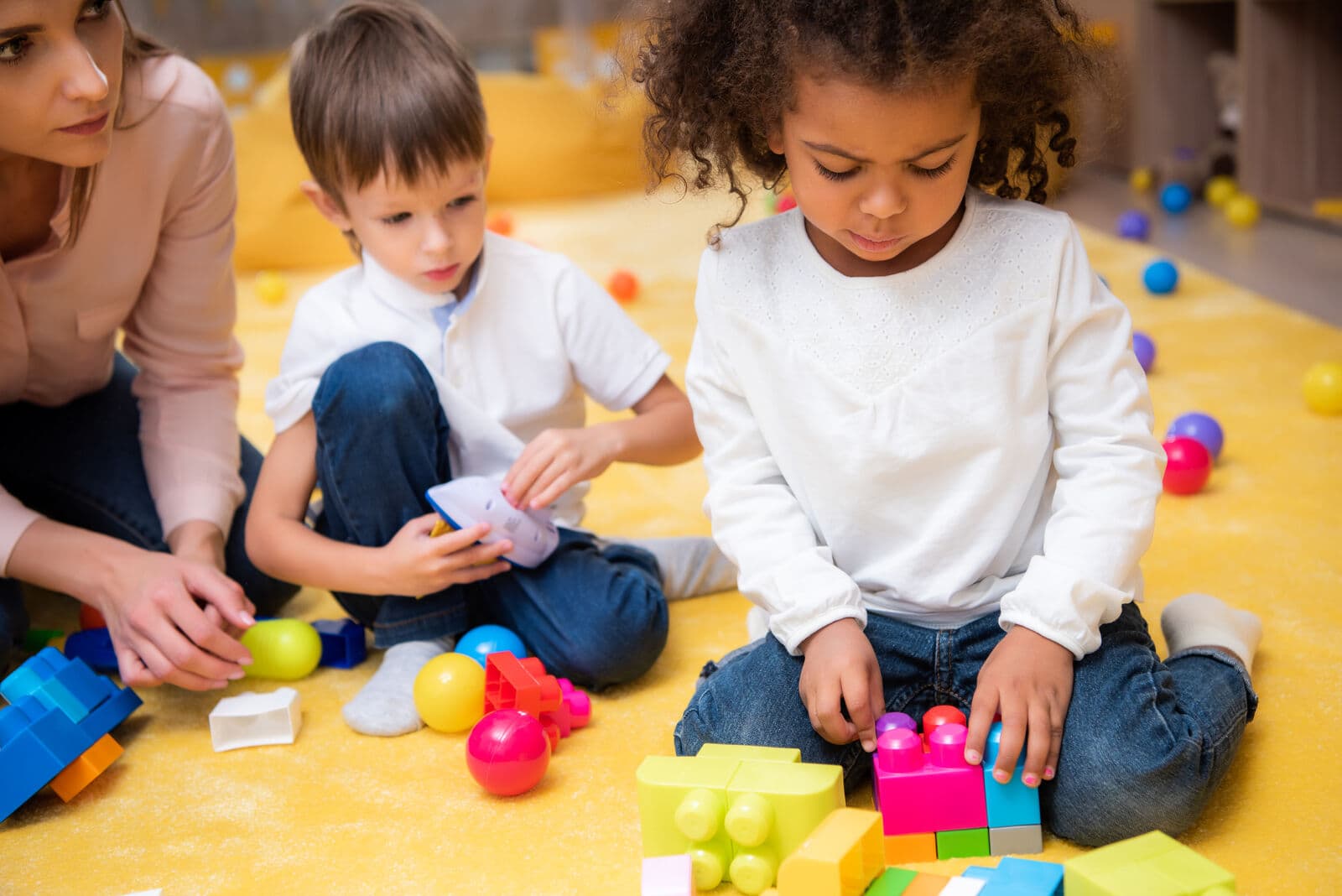 Children building blocks with a teacher